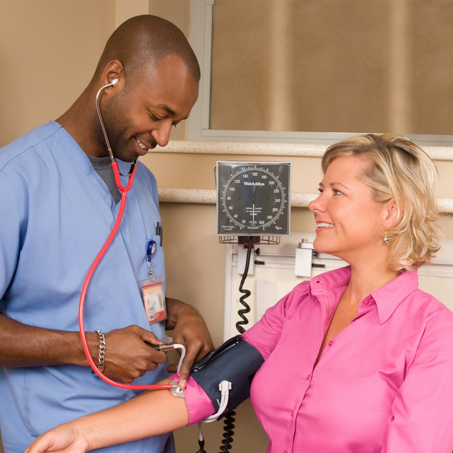 Healthcare worker checking a smiling patient's blood pressure